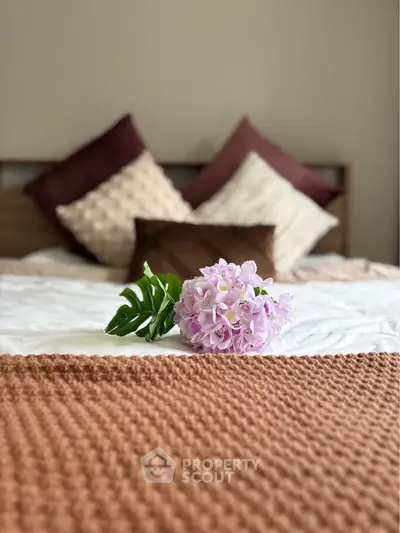 Cozy bedroom with elegant decor and plush pillows, featuring a stylish floral accent on the bed.
