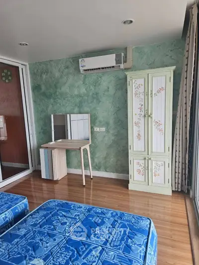 Charming bedroom with wooden flooring, air conditioning, and stylish furniture in a cozy apartment.