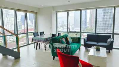 Spacious living room with city view and modern furniture in high-rise apartment.