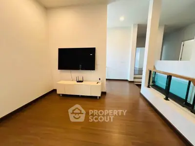Spacious modern living area with wooden flooring and wall-mounted TV, perfect for contemporary living.