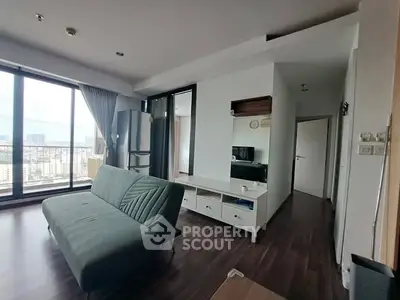 Modern living room with large windows and city view, featuring stylish furniture and sleek flooring.