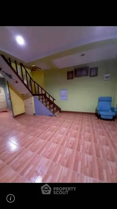 Spacious living area with wooden staircase and tiled flooring, perfect for family gatherings.