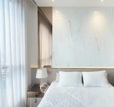 Luxurious modern bedroom with elegant marble accent wall and soft natural lighting.