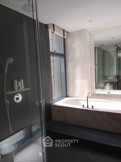 Luxurious bathroom with modern bathtub and glass shower enclosure in elegant design.