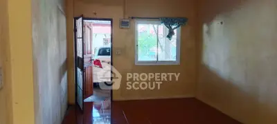 Spacious room with open door leading to carport, natural light through window.