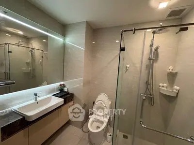 Modern bathroom with glass shower and sleek vanity in luxury apartment.