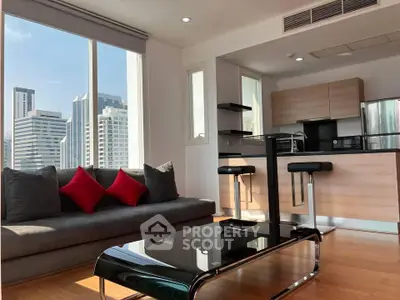 Modern living room with city view, featuring sleek furniture and open kitchen layout.