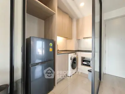 Modern compact kitchen with washing machine and fridge in sleek apartment.