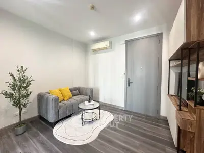Modern living room with stylish gray sofa, wooden accents, and cozy decor in a contemporary apartment.