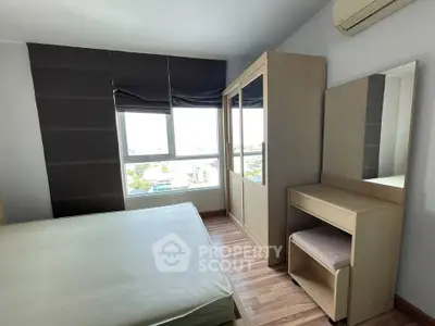 Spacious bedroom with large window and modern furniture, offering a bright and airy atmosphere.