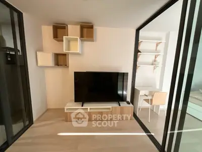 Modern living room with sleek TV setup and stylish shelving in a bright apartment.