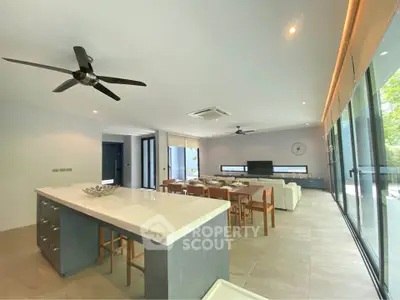 Spacious modern living room with open kitchen and large windows offering natural light.