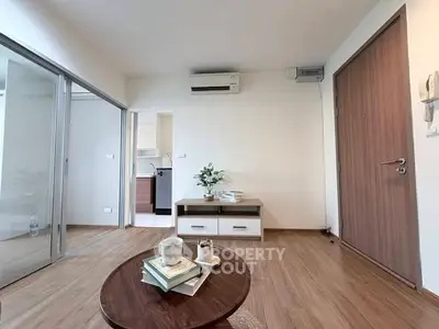 Modern living room with wooden flooring and sliding glass doors, featuring a cozy coffee table and air conditioning.