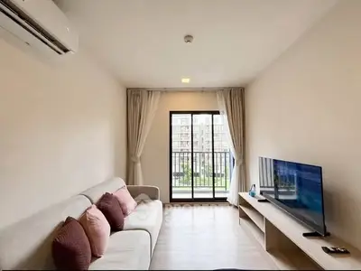 Modern living room with balcony view, featuring sleek furniture and natural light.