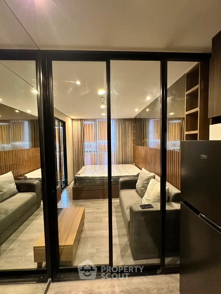 Modern studio apartment with glass partition, cozy sofa, and sleek design.