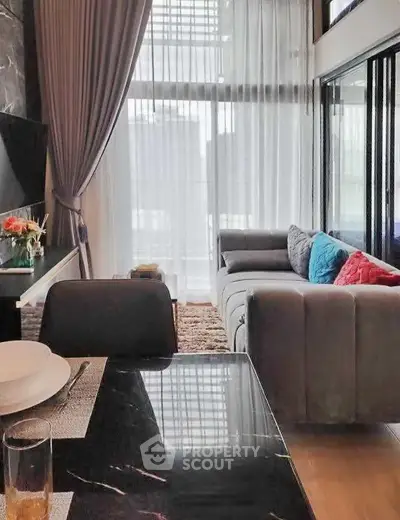 Modern living room with elegant decor and large windows offering natural light.