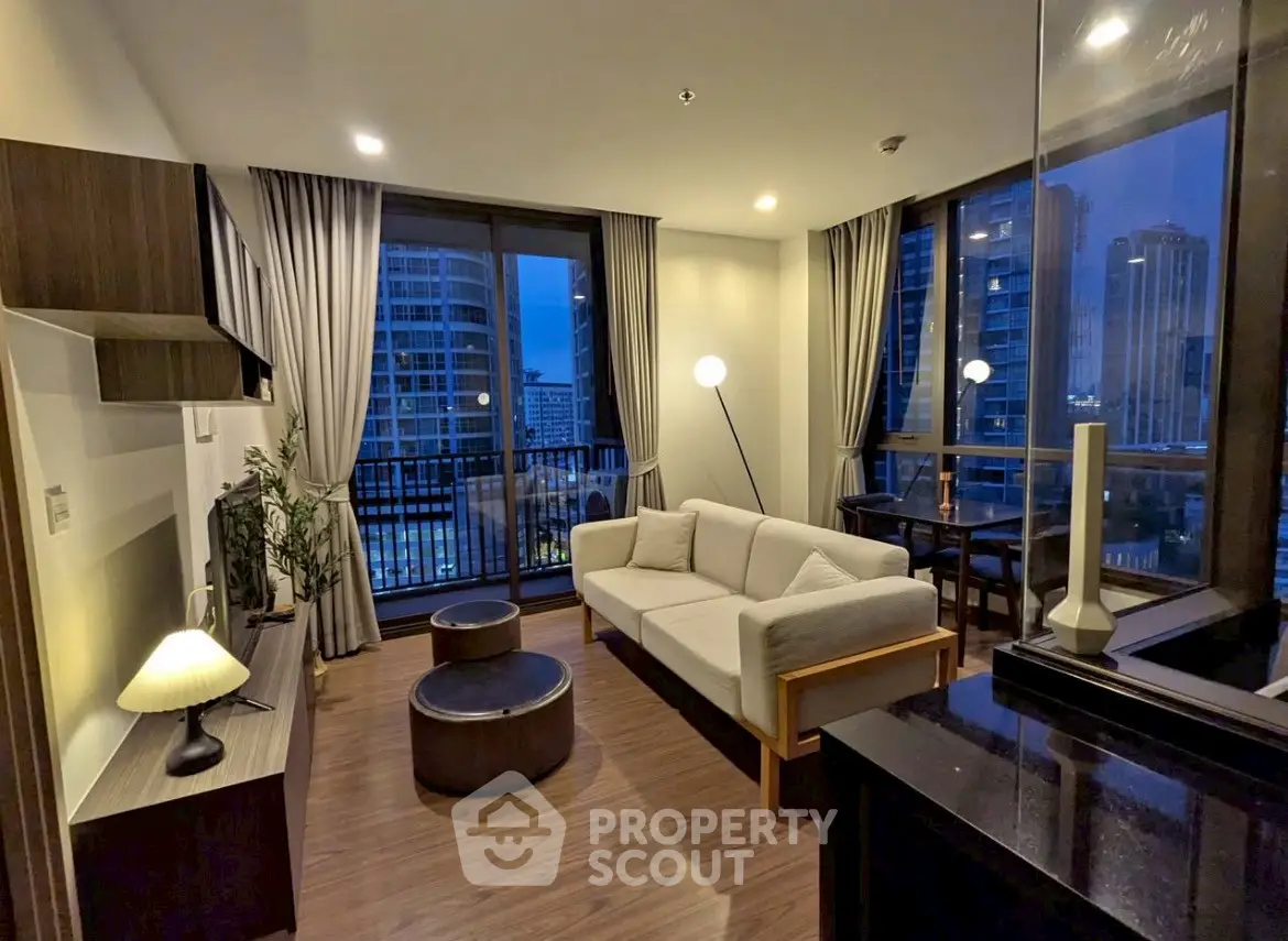 Modern living room with city view, stylish furniture, and floor-to-ceiling windows in urban apartment.
