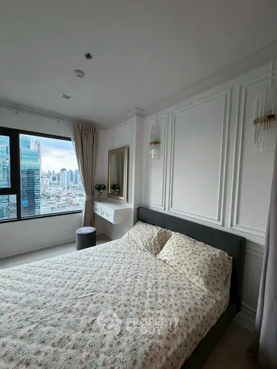 Elegant bedroom with city view, featuring chic decor and large window for natural light.
