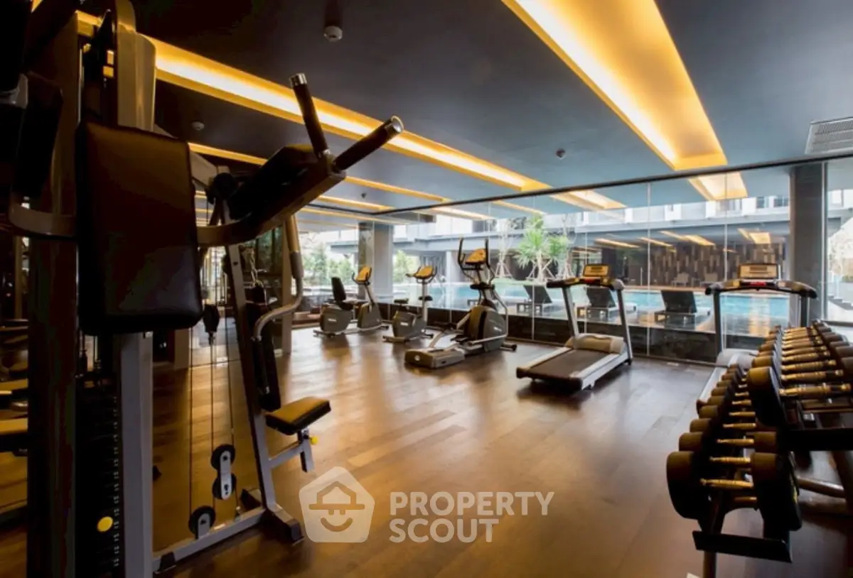 Luxurious gym with modern equipment and pool view in upscale residential complex.