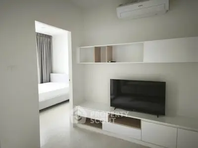 Modern minimalist living room with TV and air conditioning, adjacent to a cozy bedroom.