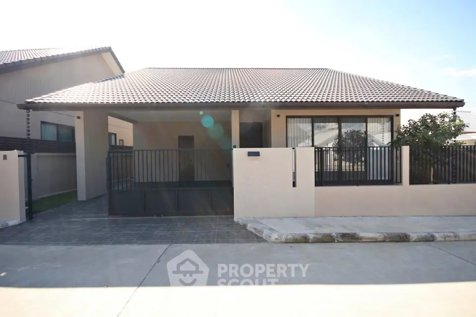 Modern single-story house with tiled roof and gated driveway in a suburban neighborhood.