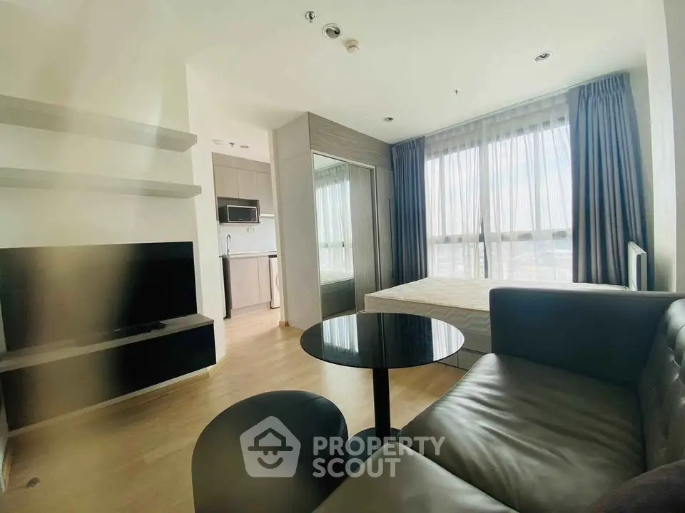 Modern studio apartment with open layout, featuring a cozy living area, kitchenette, and large windows for natural light.