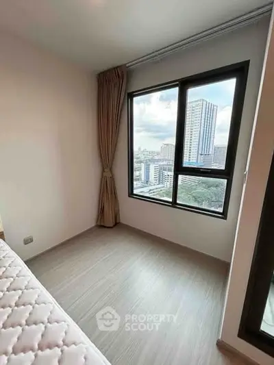 Modern bedroom with large window offering stunning city view in high-rise apartment.