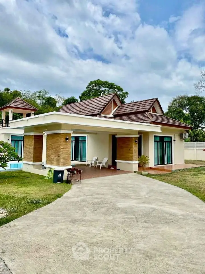 Charming single-story house with modern design, spacious driveway, and lush greenery, perfect for family living.