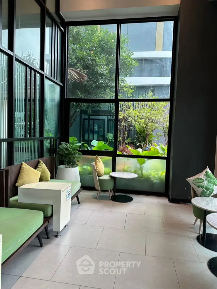 Modern lobby with large windows and stylish seating overlooking lush greenery.