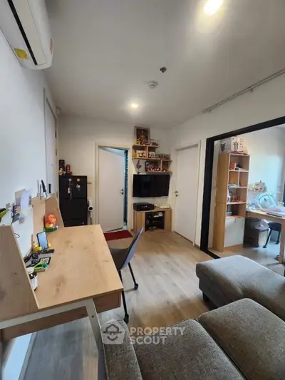 Modern living room with cozy seating and workspace, featuring stylish decor and ample natural light.