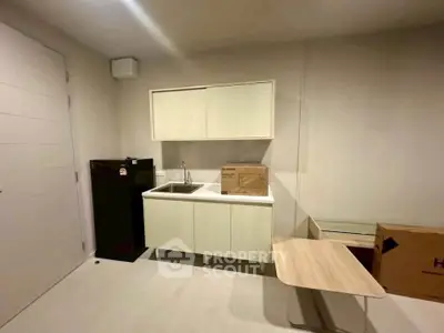 Modern compact kitchen with sleek cabinetry and small fridge in a cozy apartment setting.