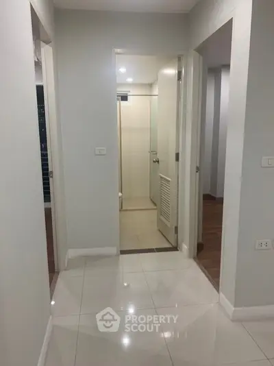 Modern apartment hallway with glossy tiled flooring and neutral walls
