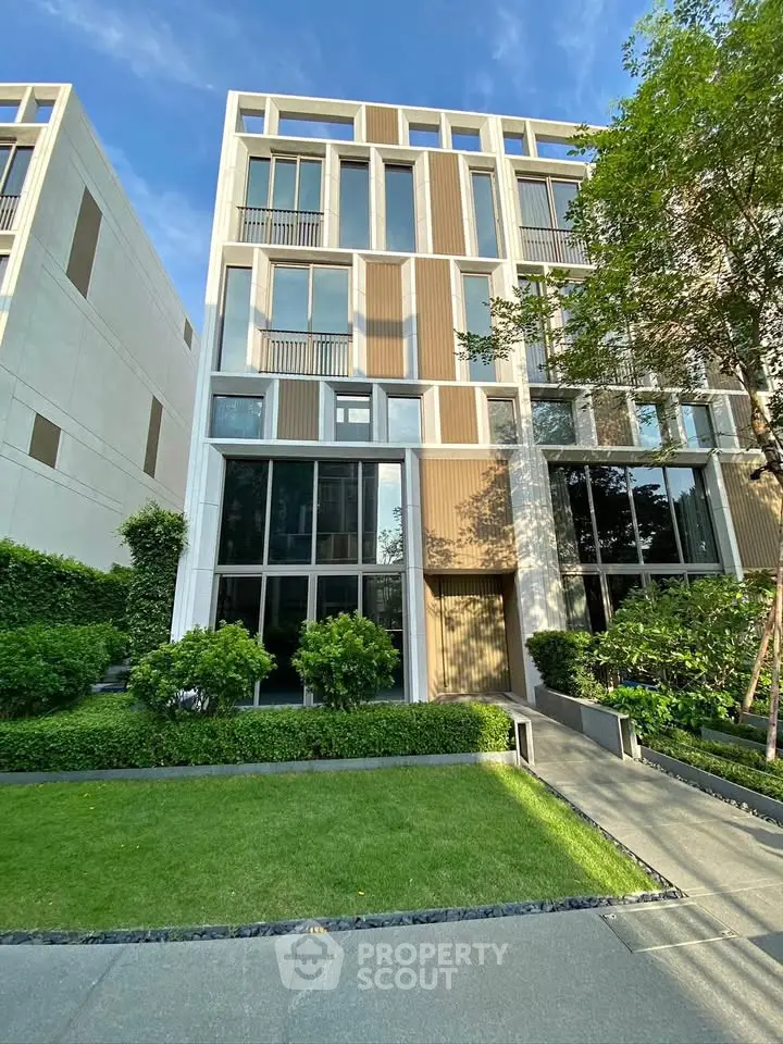 Modern multi-story building with sleek design and lush greenery in urban setting.