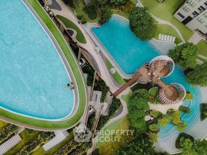 Aerial view of luxurious swimming pools and landscaped gardens in a modern residential complex.