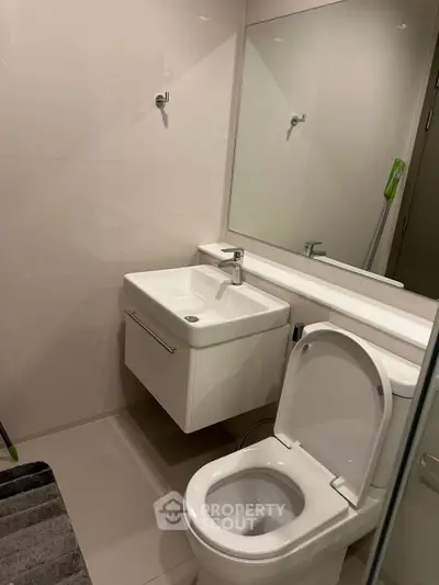 Modern bathroom with sleek fixtures and large mirror, perfect for a contemporary home.