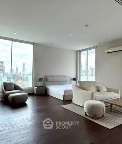 Spacious modern bedroom with city view, featuring elegant furniture and large windows.