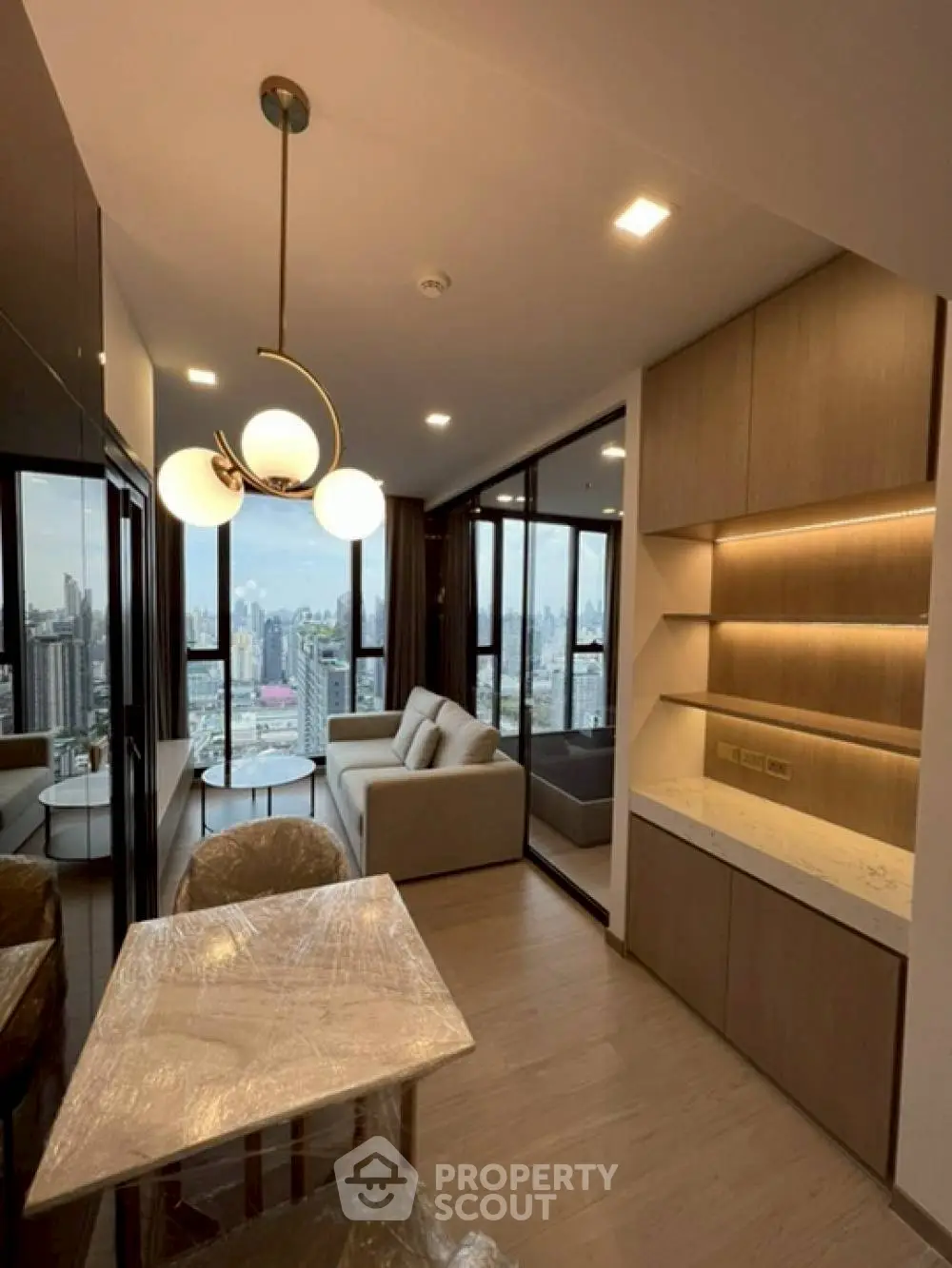 Modern living room with city view, elegant lighting, and stylish furniture in a high-rise apartment.