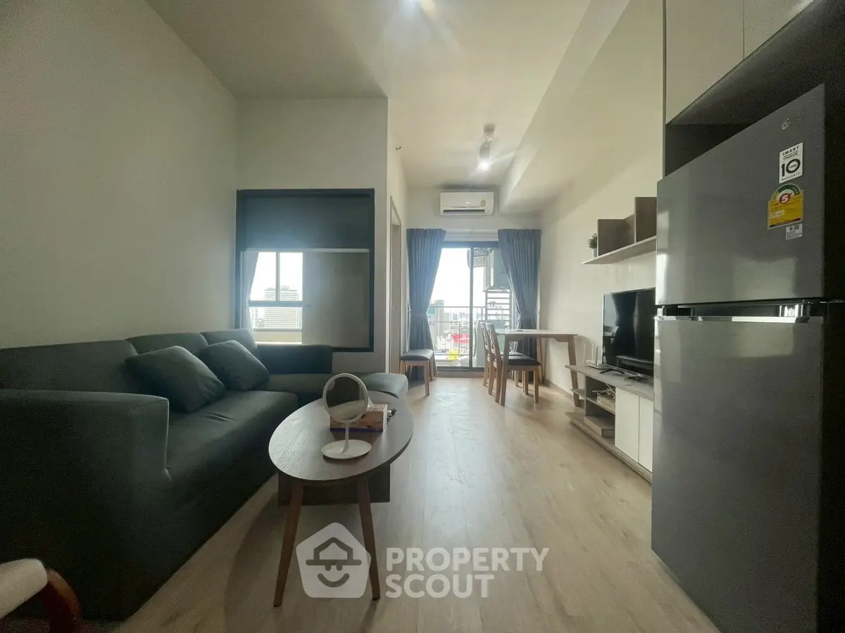 Modern living room with open layout, featuring sleek furniture and a balcony view.