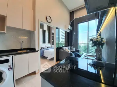 Modern open-plan kitchen and living area with city view and cozy bedroom