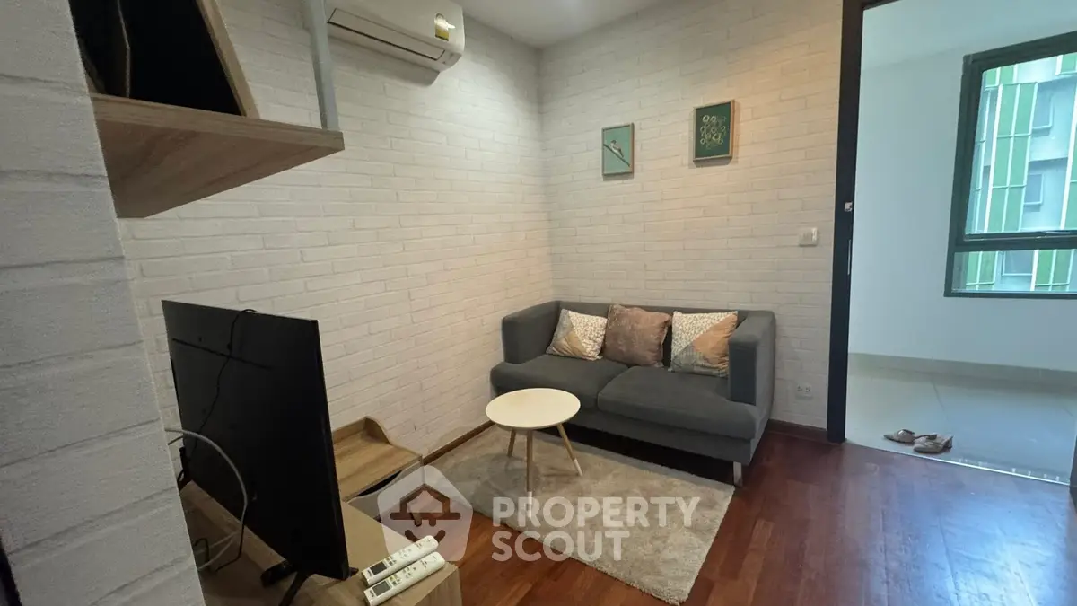 Cozy living room with modern decor and air conditioning, featuring a comfortable sofa and stylish TV setup.