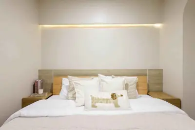 Cozy bedroom with modern decor and ambient lighting, featuring a stylish headboard and plush pillows.