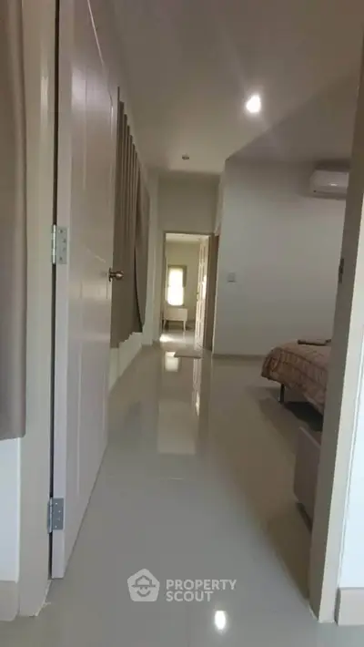 Spacious hallway leading to a cozy bedroom with modern decor and polished flooring.