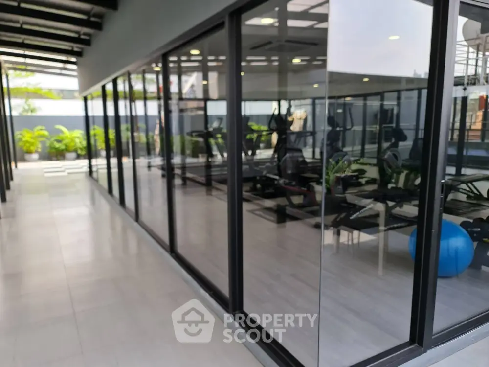 Modern gym with glass walls and fitness equipment in luxury apartment building.