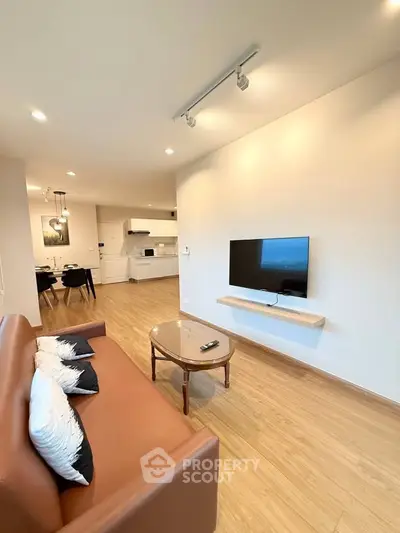 Modern living room with sleek TV setup and open kitchen layout, perfect for contemporary living.