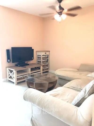Cozy living room with beige sectional sofa, TV, and stylish wooden furniture in a warm, inviting setting.