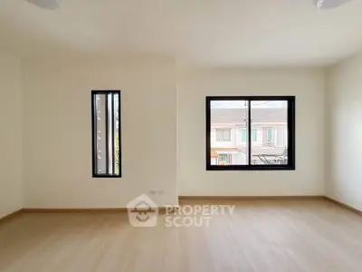 Spacious empty room with large windows and wooden flooring, ideal for customization.