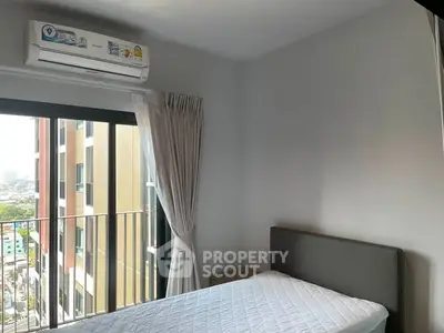 Cozy bedroom with balcony view in modern apartment, featuring air conditioning and natural light.