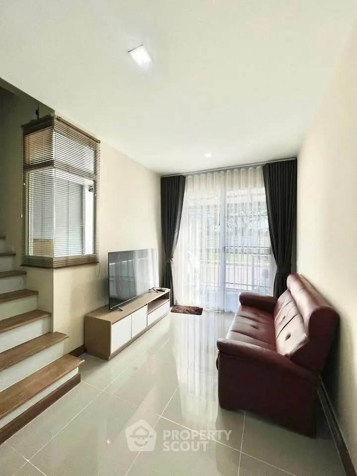 Modern living room with sleek design and natural light, featuring a cozy sofa and flat-screen TV.