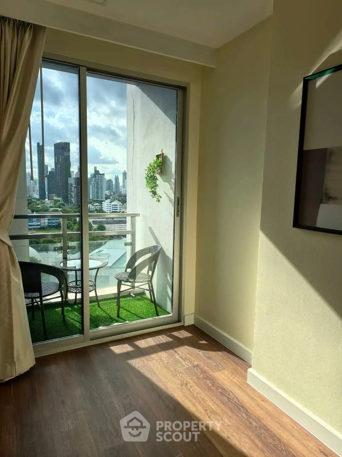 Bright room with balcony offering stunning city view and cozy seating area.