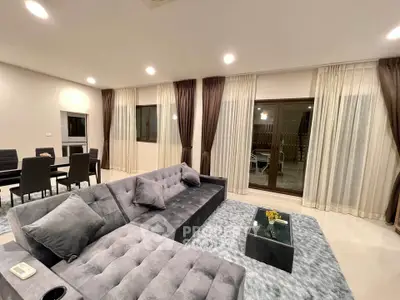 Luxurious modern living room with plush gray sectional sofa and elegant dining area.
